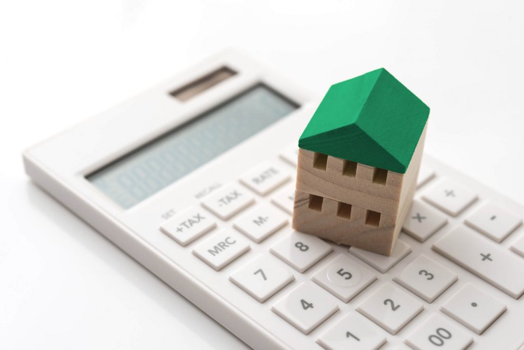 電卓とその上に置かれた緑の屋根の家