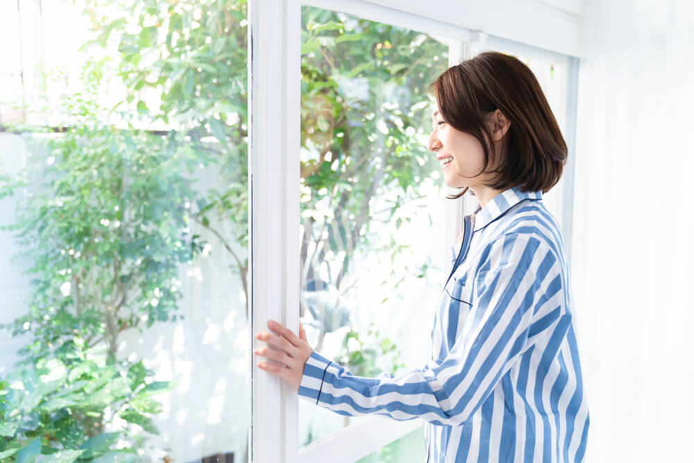 窓に手をかけて外を眺める女性