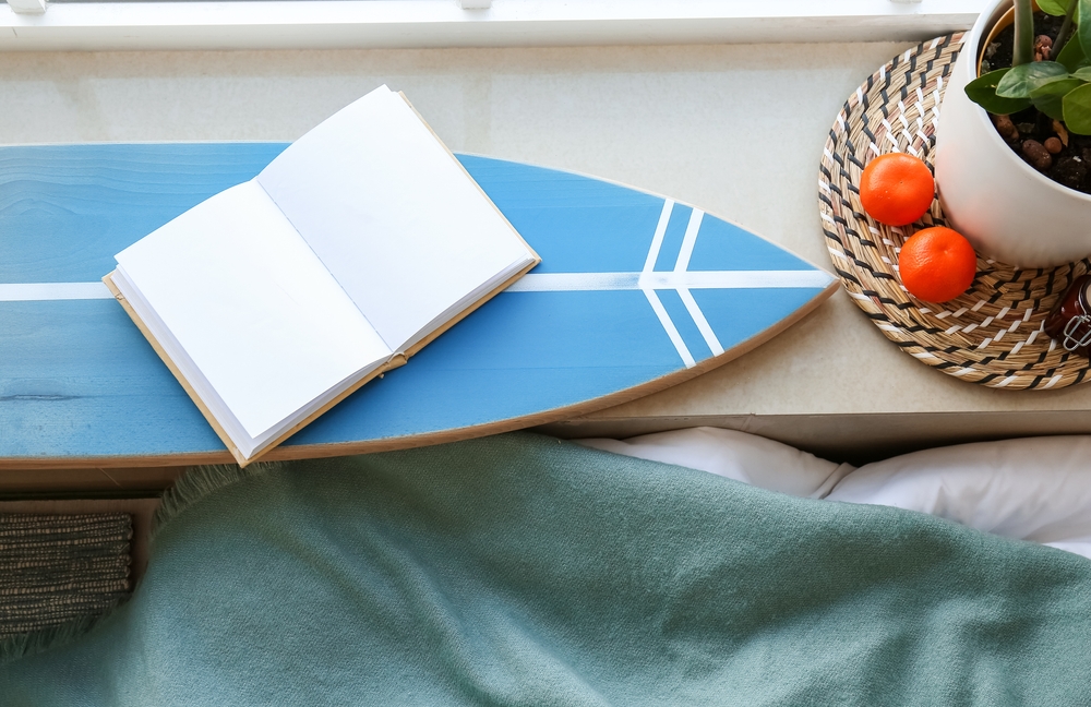 窓ぎわに置かれたサーフボードと本